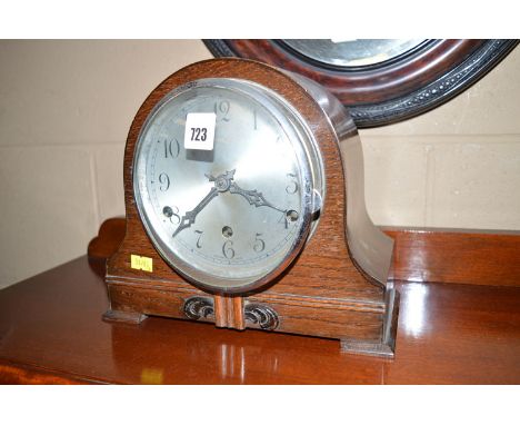 An early 20th Century oak cased mantel clock, the arabic silvered dial within an arched case with flared feet.