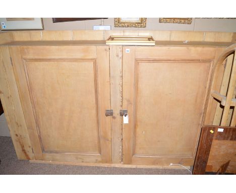 An early 20th Century stripped pine two-door cupboard, the three-quarter gallery top above a pair of panel doors enclosing sh