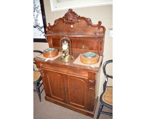 A Victorian mahogany chiffonier, the back with carved serpentine scrolling cresting rail above shaped shelf and plain panel, 