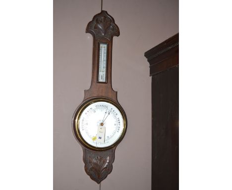 A mid 20th Century stained oak framed aneroid barometer and thermometer.