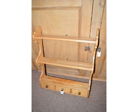 A stripped pine three-tier hanging shelf, fitted three drawers under with brass knob handles.