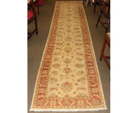 Narrow Afghan runner, the cream field of palmettes and flowering vines enclosed by terracotta borders, 383cm by 79cm