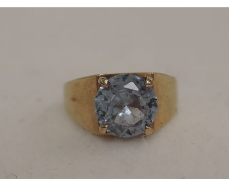 A ladies dress ring of stylised form having a blue topaz stone in a raised claw mount on a heavy 9ct gold loop