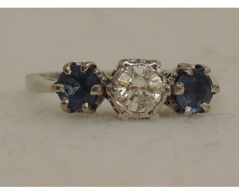 A ladies dress ring having a central diamond, approx .4ct flanked by two sapphires in a raised collar and claw mount on an 18