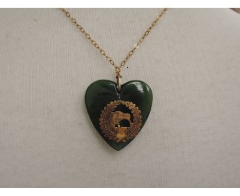 A Jade heart shaped pendant having Kiwi applique decoration to front stamped 9ct on a yellow metal chain