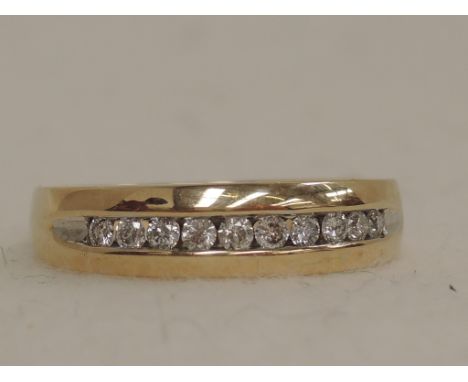 A ladies half eternity ring having 10 channel set diamonds on a yellow metal loop stamped 10K,  approx 6.6g