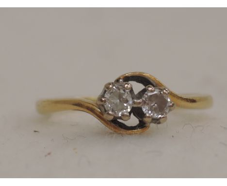 A ladies dress ring having two diamonds in a crossover setting on a yellow metal loop, no marks tested as 18ct gold