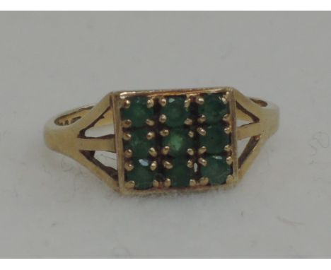 A ladies dress ring  having 9 emerald chips in a square mount on a 9ct gold loop