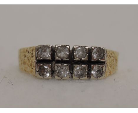 A ladies dress ring having two rows of four paste stones in square setting on bark effect shoulders on a yellow metal loop, n