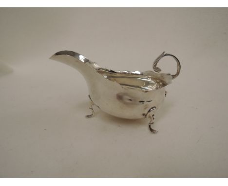 A silver sauce boat having scroll handle, shaped rim and trefoil pad feet, London 1912, Haseler Brothers,  approx 110g