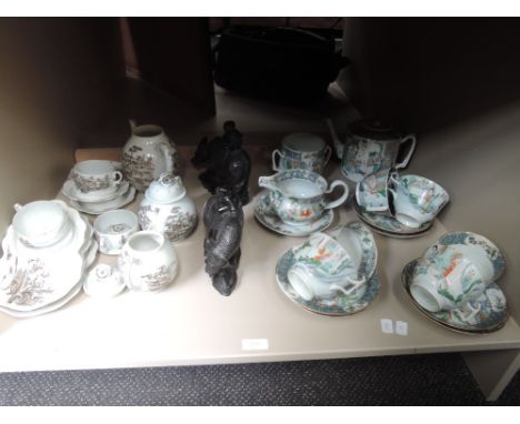 A Japanese eggshell tea service, a Japanese polychrome tea service and a pair of Japanese hardwood figures modelled as water 