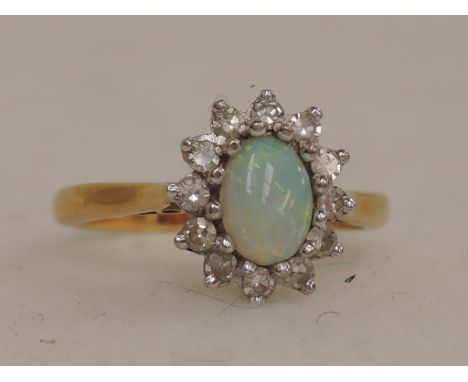 A ladies dress ring having an opal and diamond cluster in a raised basket setting on a yellow metal loop, hallmarks worn test