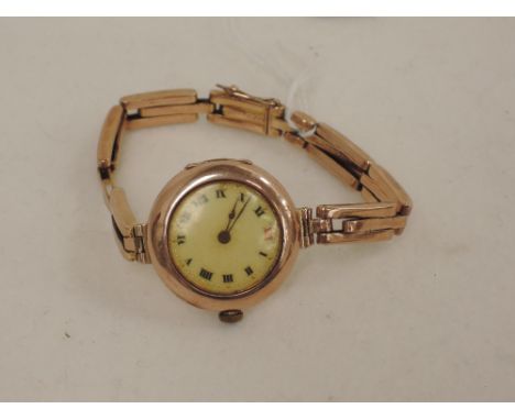 A ladies vintage 9ct gold wrist watch by Rolex having Roman numeral dial with red no 12 to a white enamel face on a yellow me
