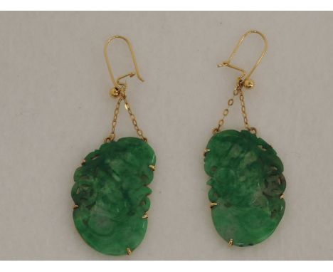 A pair of carved jade earrings in the form of Oriental mythical birds in yellow metal mounts on chain drops from loops, no ma