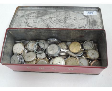 A vintage tin containing a large collection of wrist watch faces including Lucerne, Bvler, Timex, Ruhla, Novoris etc