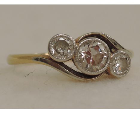 A ladies dress ring having  three diamonds, approx .7ct, in a milgrain mount to crossover shoulders on a yellow metal mount s
