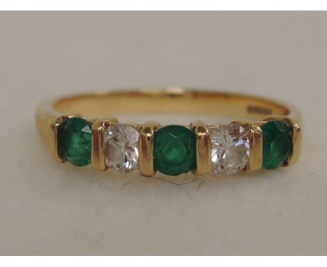 A half eternity ring having three emeralds interspersed by two diamonds on an 18ct gold loop