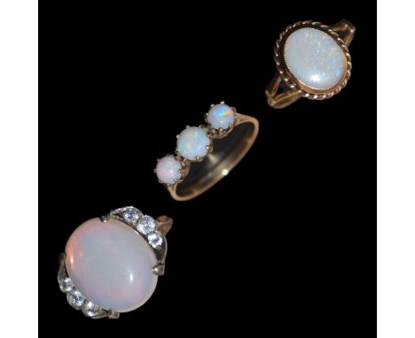 Three opal dress rings, comprising a 9ct gold ring the oval opal cabochon rubover set within a rope twist border (a/f), a thr
