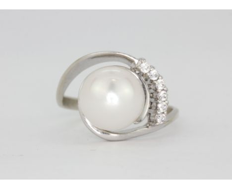 A white metal (tested 18ct gold) ring set with a large cultured 10mm pearl and brilliant cut diamonds, (R ).