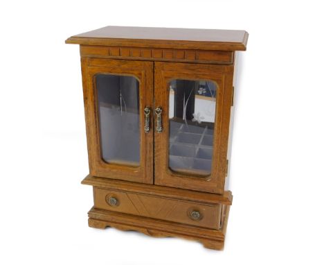An oak cased musical jewellery cabinet, playing Feelings, the outswept pediment over two floral engraved glazed doors, above 