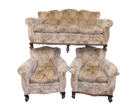 An early 20thC oak three piece suite, upholstered in floral patterned fabric, raised on ball &amp; claw feet, on castors, com