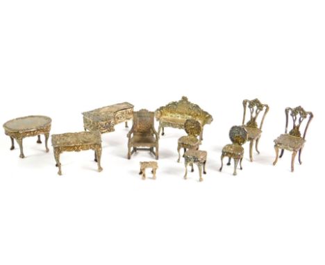 A suite of miniature silver furniture, repousse decorated with cherubs and flowers, comprising a two seater sofa, oval table,