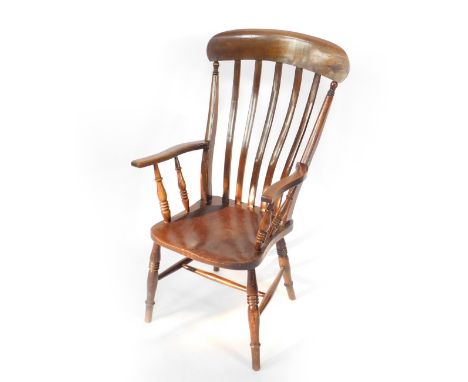 A Victorian oak and elm lath back kitchen chair, with turned arms and solid saddle seat, raised on ring turned legs united by