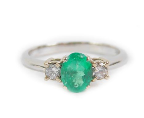 An emerald diamond and platinum three stone ring, the oval cut emerald approx 0.7cts, diamonds approx 1/8th carat, size P, 4.