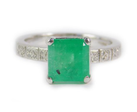 A platinum emerald and diamond ring, the square cut emerald in a claw setting with diamond pave set shoulders, emerald approx