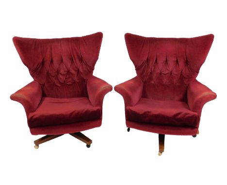 A pair of G-Plan Blofeld swivel armchairs, with red button back fabric, raised on a rosewood base, on castors. N.B. With CITE