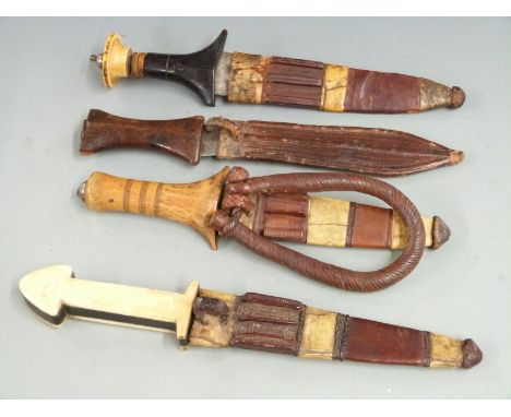 Four African tribal daggers, each with leather scabbard and shaped handle