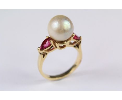 A 14ct Yellow Gold and Pearl Ring. The pearl approx 10mm and flanked by two pear-shaped rubies approx 6 x 4 mm each, size L, 