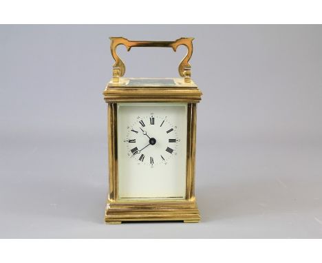A Brass English Carriage Clock. The clock with white enamel face and Roman numerals, approx 8 x 6 x 12 cms (excluding handle)