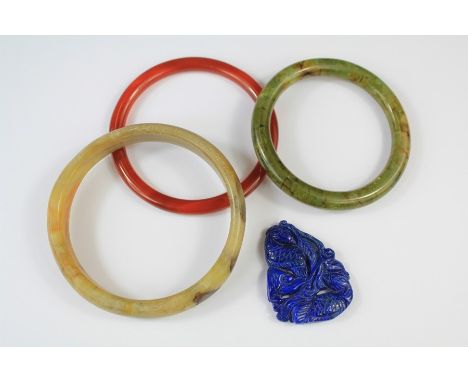 Three Chinese Hard-stone Bangles. This lot includes a red agate bangle, green jade bangle, green and white jade and a blue st