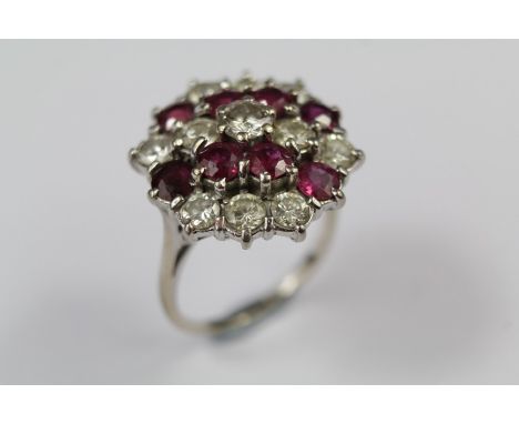 An 18ct Gold Ruby and Diamond Cluster Dress Ring. The ring set with eight rubies approx 3.5mm each and a single diamond appro