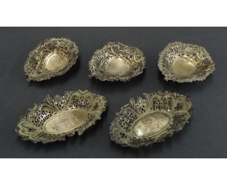 Pair of late Victorian silver trinket dishes with acanthus scrolls and pierced geometric panels; together with three white me