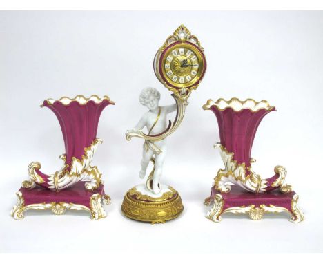 A Dresden Porcelain Mantle Clock, the central cherub holding the scrolling circular dial with Roman numerals, hanging pendulu