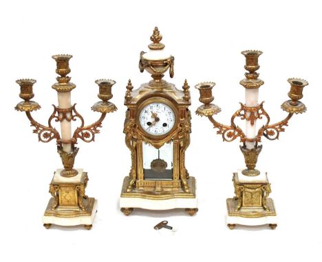 An Early XX Century French Ormolu and White Marble Clock Garniture, of elaborate form surmounted by a floral urn, the rectang