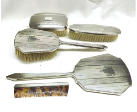 A Four Piece Silver Backed Dressing Table Set comprising Hand Mirror, Three Brushes and a Comb, all with engine turned decora