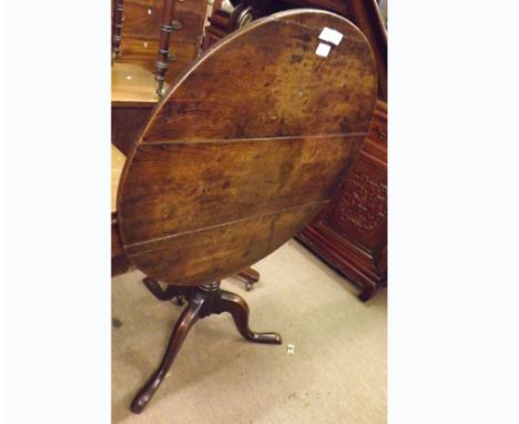 An 18th Century Oak tilt-top round Table, raised on a turned pedestal and spreading tripod base, the top 30” diam 