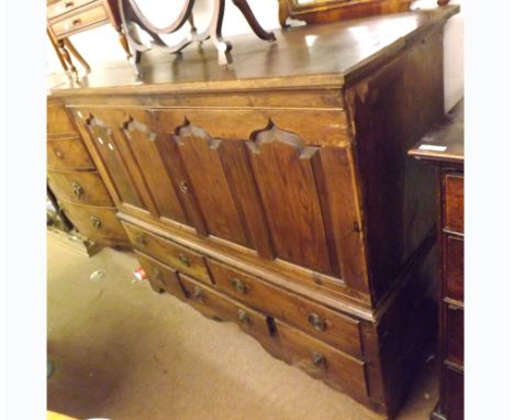 An 18th Century and later Oak Side Cabinet, two panelled doors over two long and three short drawers, with brass lion mask ha