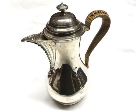 A George III Hot Water Jug of plain circular baluster form, having cane clad handle, urn finial to the hinged lid, beaded pou