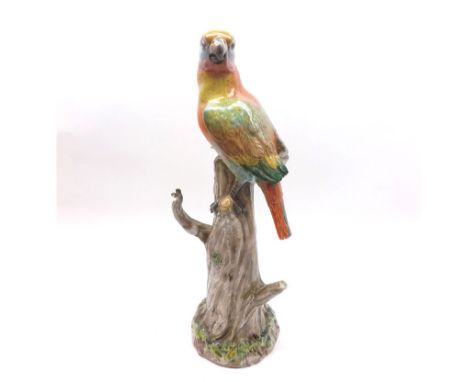 A 20th Century Continental Model of a parrot on a tree trunk, decorated throughout in colours, (losses to tips of wings and t