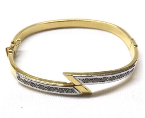 High grade precious metal hollow bangle of cross-over design set with white stones stamped “18ct” weighing approximately 12gm