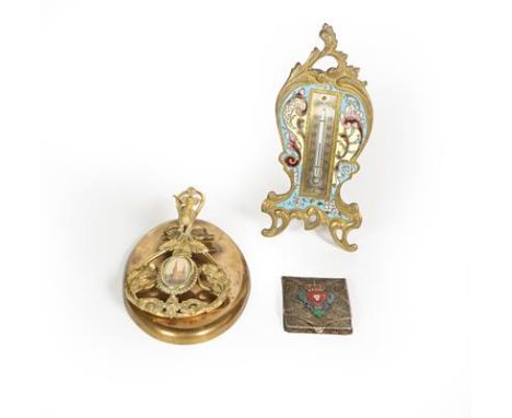 A French Brass and Enamel Thermometer, with easel-back, 17cm high; A brass paperweight, the base oval, with openwork clip app