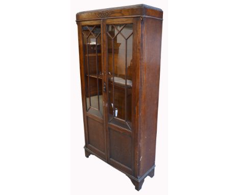An early 20th century oak glazed bookcase on bracket feet (lacking interior shelves).