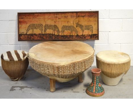 A circular hide covered drum table on triple block supports, width 86cm, three similar drums to include one with a terracotta