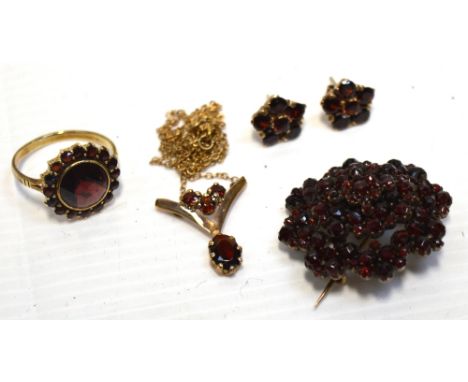 A white metal floral brooch set with garnets, a 9ct gold ring with large circular garnet surrounded by small ones, size J and