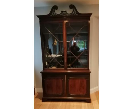 An  Edwardian mahogany two-stage bookcase in Edwards &amp; Roberts style, the open-fret swan neck pediment above a pair of as