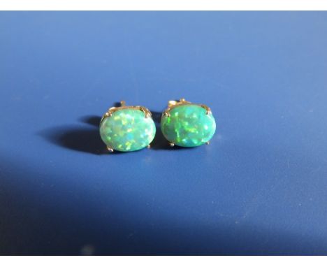 A pair of green opal stud earrings claw set in '14k' yellow metal.